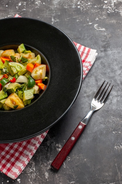 Salada de tomate verde vista inferior em prato oval um garfo em fundo escuro