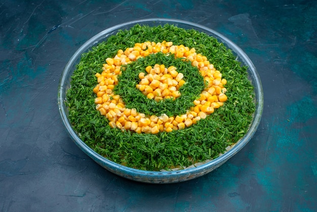 Salada de verduras meia vista com calos dentro de uma placa de vidro redonda sobre fundo azul escuro.