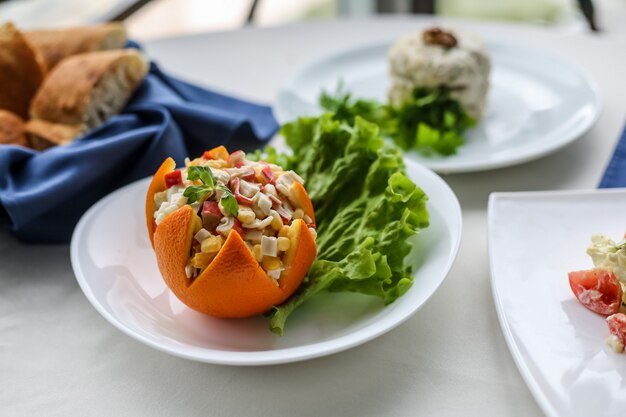 Salada de vista lateral em casca de laranja com uma folha de alface em um prato