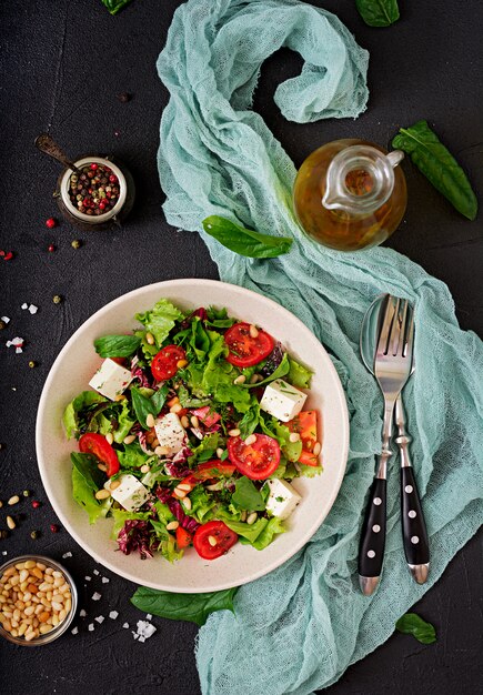 Salada dietética com tomate, queijo feta, alface, espinafre e pinhões. Vista do topo. Postura plana.