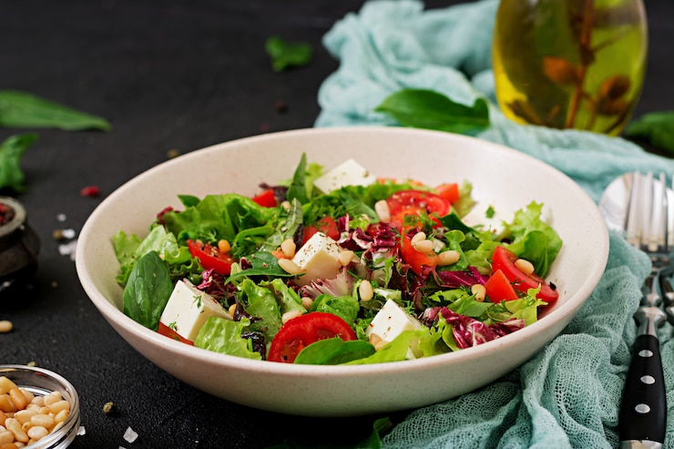Foto grátis salada dietética com tomate, queijo feta, alface, espinafre e pinhões.