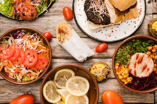 Salada; fatias de limão com hambúrguer; tigela de burrito e envoltório na mesa