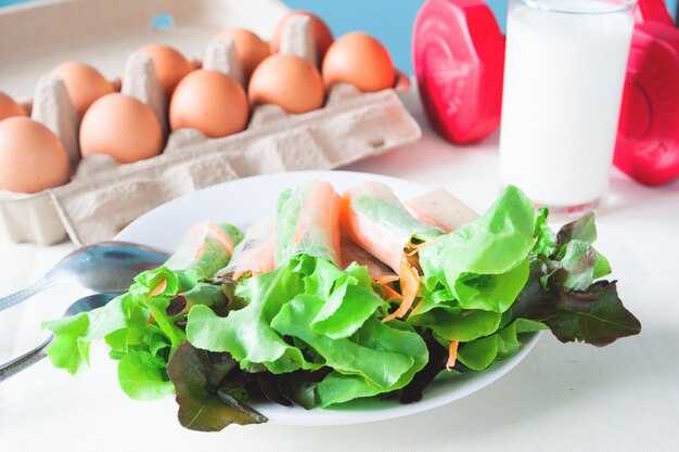 Salada fresca com ovo e leite, Menu saudável com dumbbell vermelho, conceito de estilo de vida saudável