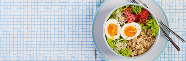 Salada fresca. Tigela de café da manhã com aveia, tomate, alface, microgreens e ovo cozido. Comida saudável. Tigela de Buda vegetariano. Vista superior, plana