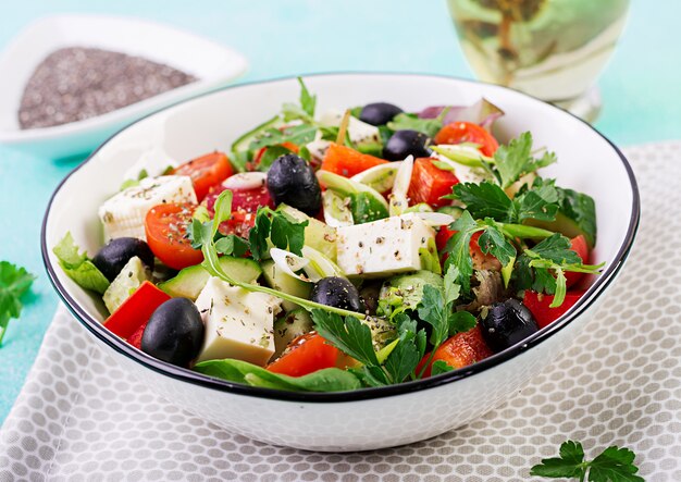 Salada grega com pepino, tomate, pimentão, alface, cebola verde, queijo feta e azeitonas com azeite de oliva. Comida saudável.