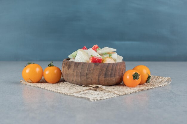 Salada mista de vegetais em um copo de madeira na mesa de concreto.