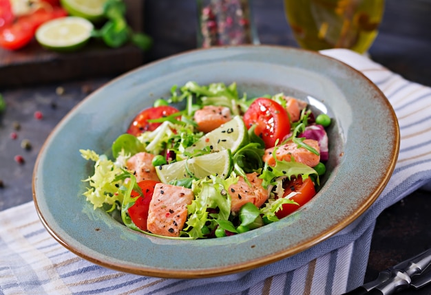Salada saudável com peixe. Salmão assado, tomate, limão e alface. Jantar saudável.