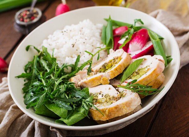 Salada saudável com rolos de frango, rabanetes, espinafre, rúcula e arroz. Nutrição apropriada. Menu dietético