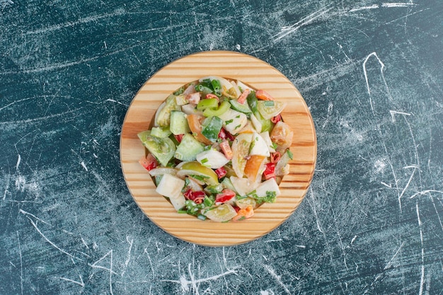 Salada sazonal com ingredientes mistos em uma travessa de madeira.
