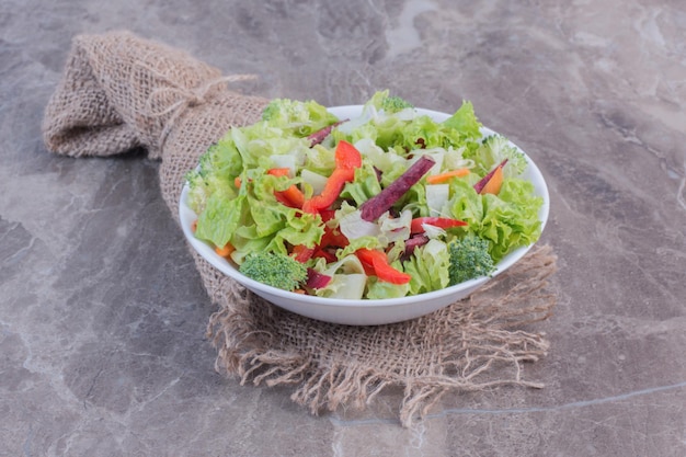 Salada simples feita de folhas de repolho picadas, cenoura, pimentão, beterraba, cebola e brócolis em superfície de mármore