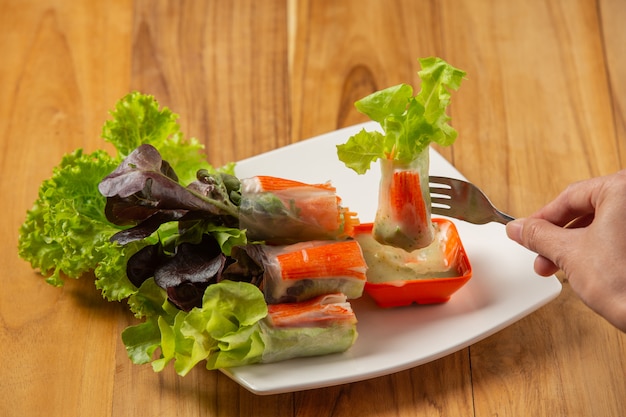 Salada tailandesa Rolls com molho picante de alho colocado em um piso de madeira.