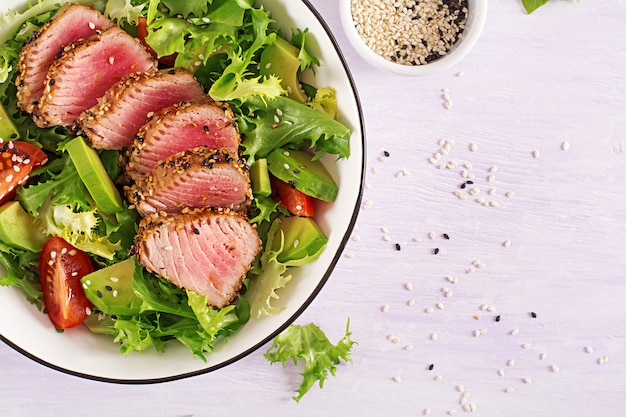 Salada tradicional japonesa com pedaços de atum Ahi grelhado médio-raro e gergelim com legumes frescos em uma tigela.