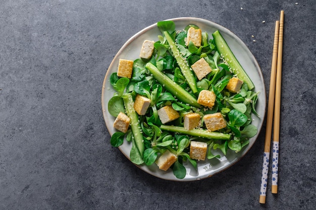 Salada vegana com pepino tofu e gergelim servido no prato Closeup