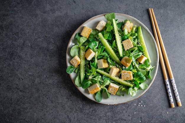 Salada vegana com pepino tofu e gergelim servido no prato Closeup