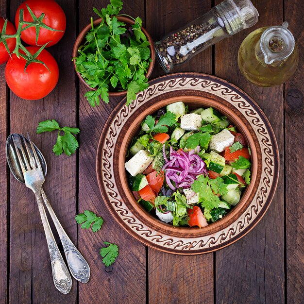 Salada vegetariana com tomate cereja, queijo brie, pepino, coentro e cebola vermelha. Cozinha americana. Vista do topo. Configuração plana