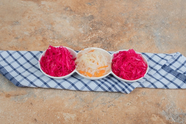 Foto grátis saladas de chucrute vermelho e branco em tigelas brancas com toalha de mesa