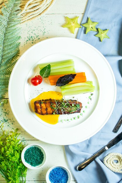 salmão assado superior servido com legumes frescos e ervas no prato branco