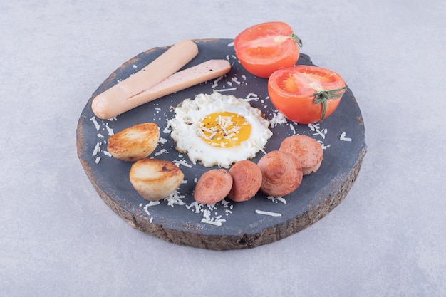 Salsichas cozidas e fritas com ovo na peça de madeira.