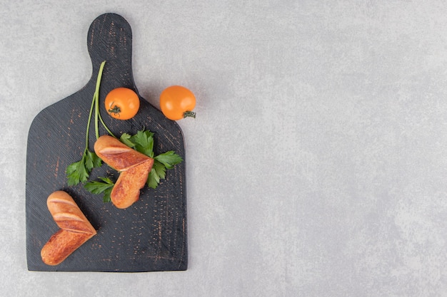 Salsichas fritas com tomate no quadro negro.