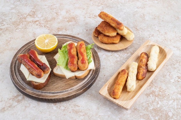 Salsichas fritas e palitos de queijo em torradas de sanduíche com limão.