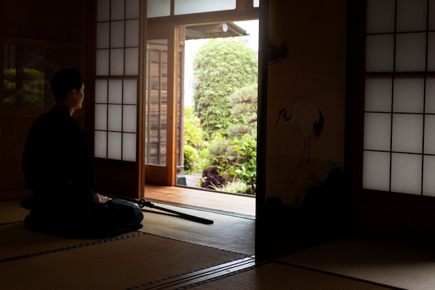 Samurai de tiro completo meditando dentro de casa