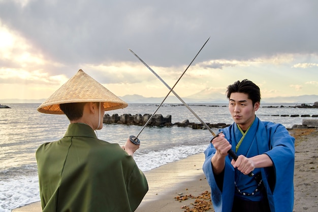 Foto grátis samurais lutando com espadas na praia