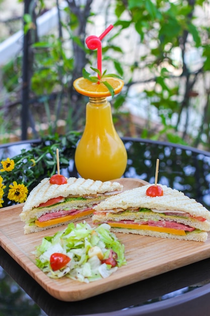 Sanduíche com suco de laranja na mesa de vidro preto