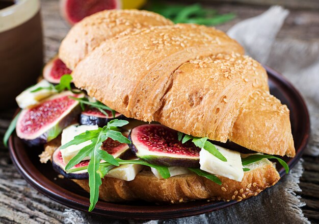 Sanduíche de croissant fresco com rúcula de queijo brie e figos. Delicioso café da manhã. Comida saborosa.