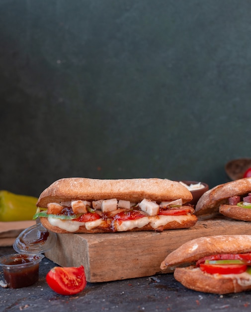 Foto grátis sanduíche de frango com cubos de queijo feta no pão baguete em uma placa de madeira