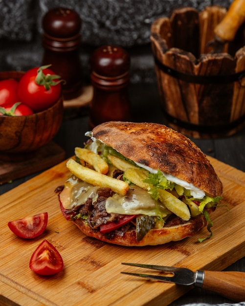 Sanduíche de pão com carne, batatas fritas e legumes.