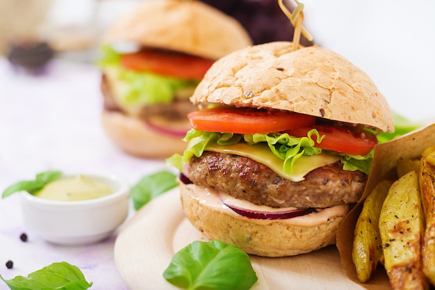 Sanduíche grande - hambúrguer com hambúrguer de carne suculenta, queijo, tomate e cebola roxa e batata frita.