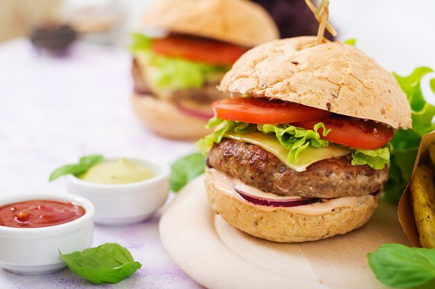 Sanduíche grande - hambúrguer com hambúrguer de carne suculenta, queijo, tomate e cebola roxa e batata frita.