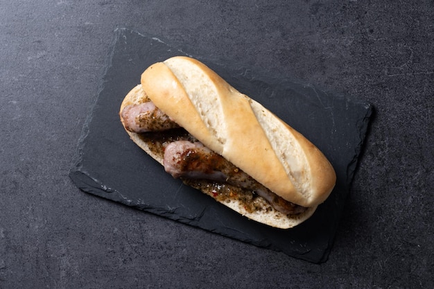 Foto grátis sanduíche tradicional de choripan argentino com molho de chorizo e chimichurri em fundo de ardósia preta