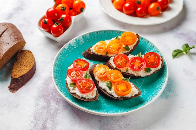 Sanduíches abertos com queijo cottage, tomate cereja e manjericão.