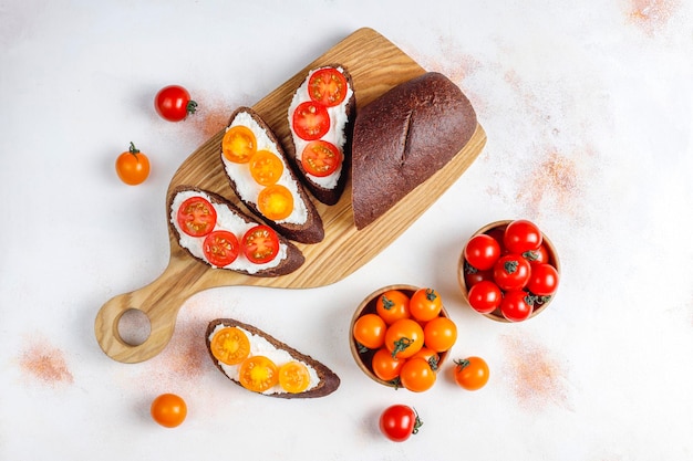 Sanduíches abertos com queijo cottage, tomate cereja e manjericão.