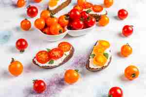 Foto grátis sanduíches abertos com queijo cottage, tomate cereja e manjericão.