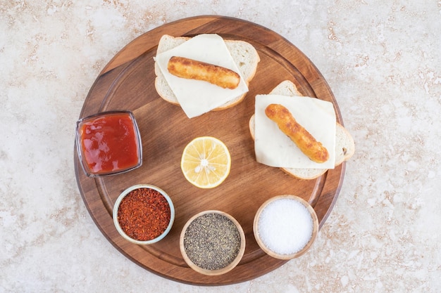 Sanduíches de linguiça grelhada com ketchup em uma placa de madeira.