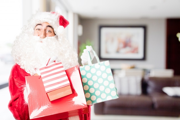 Santa com sacos de compra coloridos em uma casa