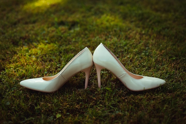 Sapatos de casamento brancos ficam de costas para trás na grama verde