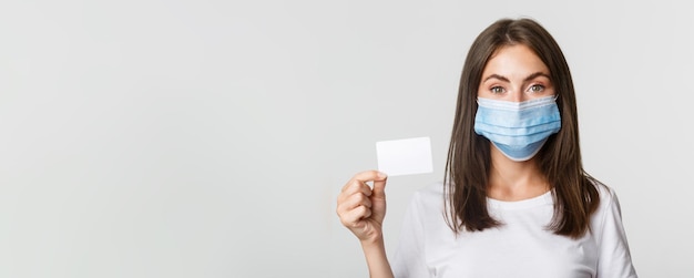 Foto grátis saúde covid e conceito de distanciamento social aproximado de uma linda morena com máscara médica mostrando c