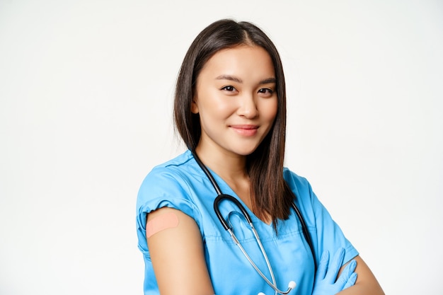 Saúde e conceito médico vacinado médico feminino asiático mostrando o braço com adesivo após vacinação covid ...