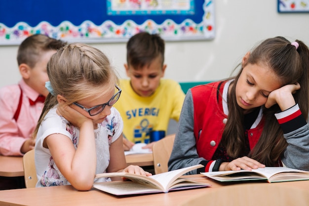 Schoolgirls sentado na mesa de leitura de livros