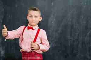 Foto grátis schoolkid elegante que gesticula no quadro-negro