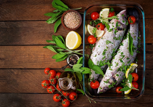 Seabass dois cru em uma assadeira com especiarias em uma mesa de madeira velha. Vista do topo