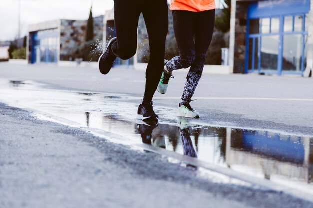 Seção baixa de dois atletas correndo na rua