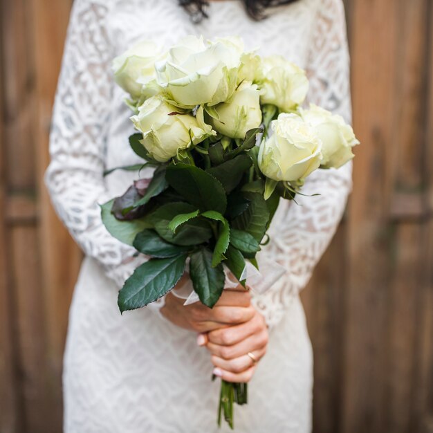 Seção intermediária da noiva segurando o buquê de rosas