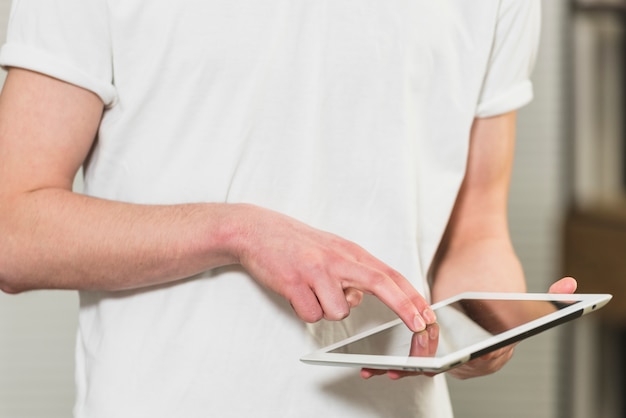 Seção intermediária de um homem tocando a tela do tablet digital com os dedos