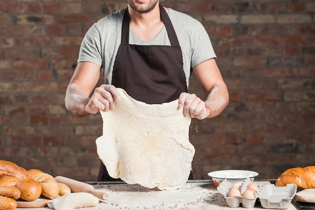 Foto grátis seção intermediária do homem preparando massa achatando na bancada da cozinha