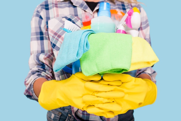 Seção intermediária do limpador segurando balde com produtos de limpeza usando luvas amarelas