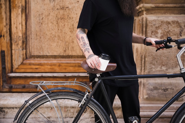 Seção mid, de, um, posição homem, com, bicicleta, segurando, takeaway, xícara café